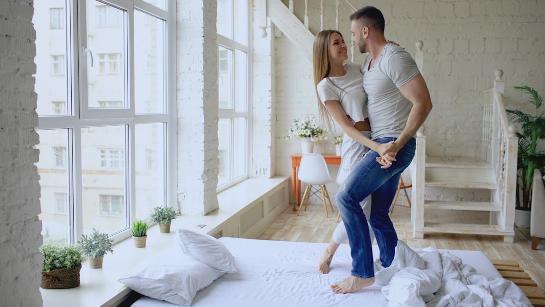 Person unpacking their suitcase on a neatly made bed in a bright, sunlit bedroom of a vacation rental, creating a sense of...