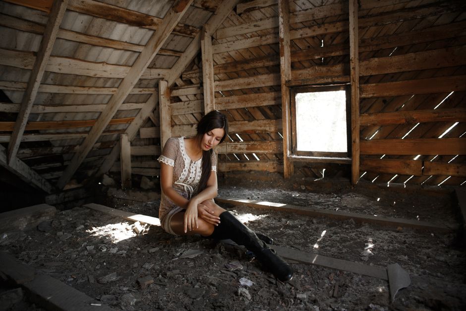 Sunlight streams through the exposed wooden rafters of a home's attic, highlighting the critical need for proper insulation against heat.